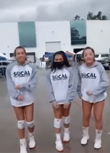 Three girls dancing  in white hoodie with gray sleeves and hoodie with large black SoCal logo across front